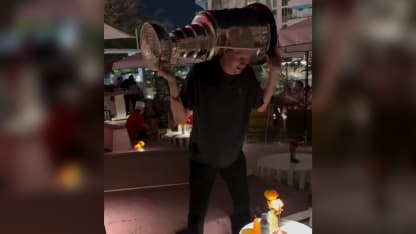 Niko Mikkola squats with Stanley Cup
