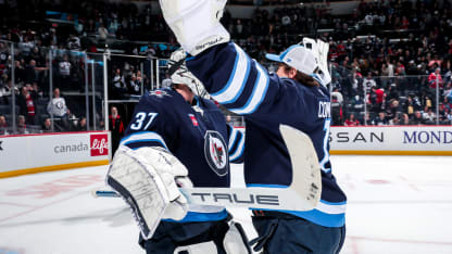 Goaltenders Connor Hellebuyck #37 and Eric Comrie #1 of the Winnipeg Jets celebrate on the ice following a 4-2 victory over the Montreal Canadiens at the Canada Life Centre on December 14, 2024 in Winnipeg, Manitoba, Canada. (Photo by Darcy Finley/NHLI via Getty Images)