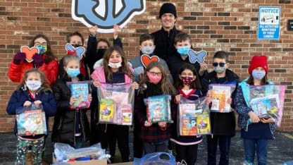 Photo of Blue Jackets player, Jack Roslovic, posing with a class of students.