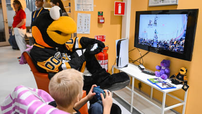 Penguins mascot playing video games at cancer center visit