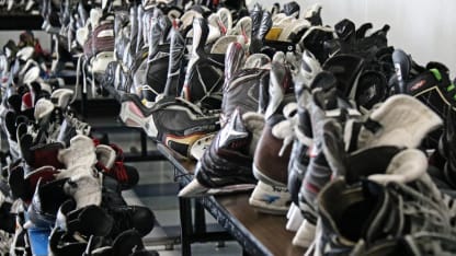 Photo of a long row of hockey skates set out on a table.