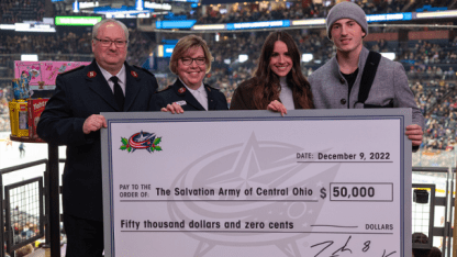 Photo of Blue Jackets alternate captain, Zach Werenski, and girlfriend posing for a photo with representatives from the Salvation Army of Central Ohio. They are holding up a large Blue Jackets check given to the Salvation Army for fifty thousand dollars.