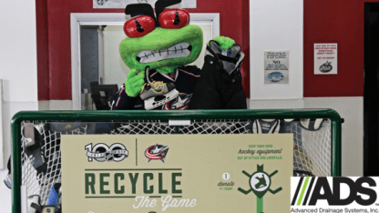 Photo of Blue Jackets mascot, Stinger, holding up hockey skates and pants for a photo at the Blue Jackets Equipment Sale.