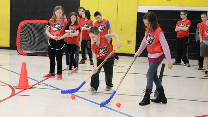 Photo of two young children stick handling with hockey sticks and balls during a Blue Jackets Power Play Challenge event.