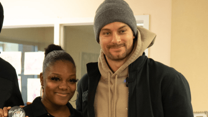 Photo of Blue Jackets player, Sean Kuraly, posing for a photo with a woman holding a signed Blue Jackets hockey puck at the Van Buren Center Family Shelter.