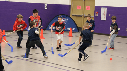 Photo of a group of young children playing street hockey at a Power Play Challenge event.
