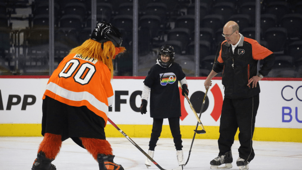 Flyers Alumni Brad Marsh and Gritty skating with youth participant for a learn to skate on Pride night