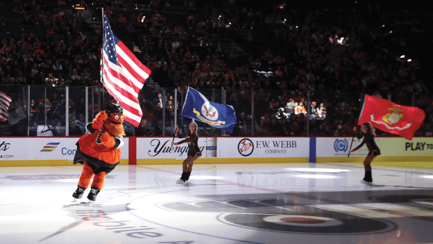 Gritty and Flyers Ice Team skate with military flags