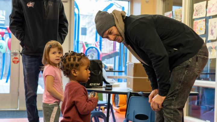 Photo of Blue Jackets player, Sean Kuraly, interacting with a young child at the Van Buren Center Family Shelter.