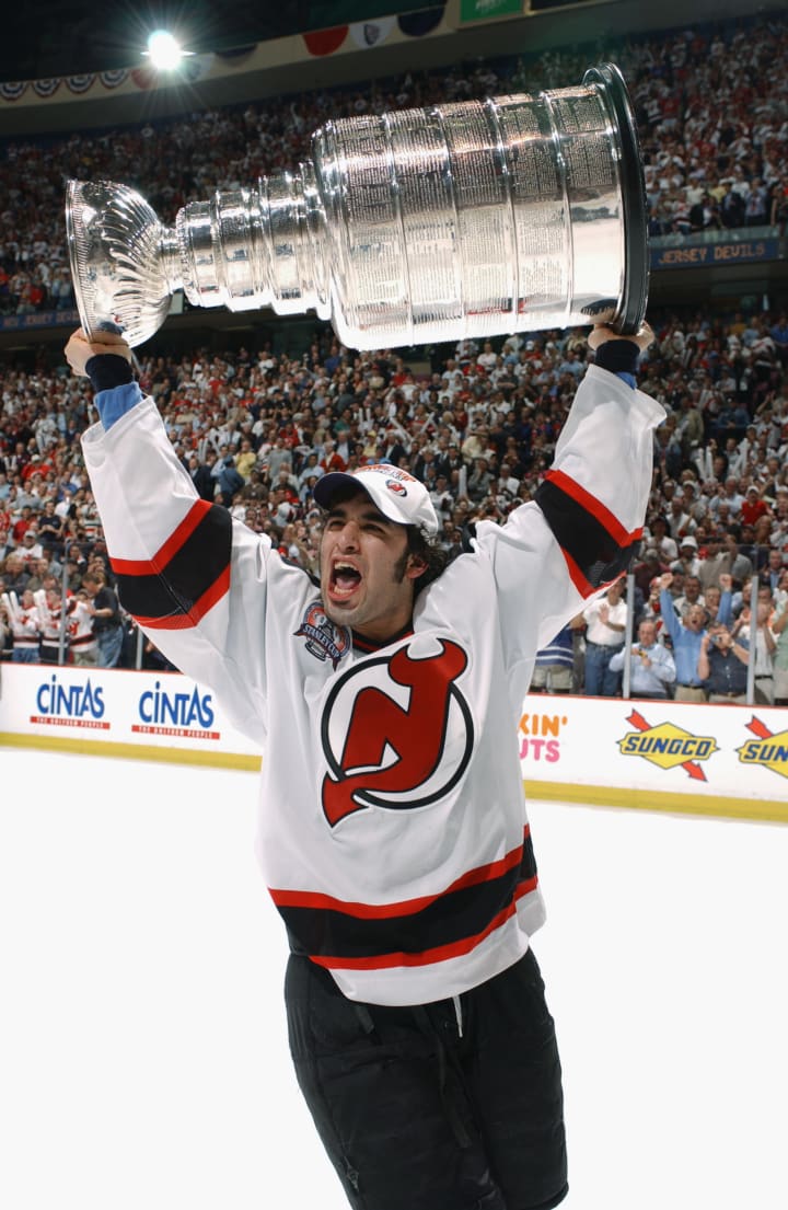 Scott Gomez #23 of the New Jersey Devils rasies the Stanley Cup after defeating the Mighty Ducks of Anaheim in game seven of the 2003 Stanley Cup Finals at Continental Airlines Arena on June 9, 2003 in East Rutherford, New Jersey. The Devils defeated the Ducks 3-0 to win the Stanley Cup. (Photo by Dave Sandford/Getty Images/NHLI)