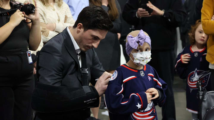 Photo of Blue Jackets player, Zach Werenski, signing the back of a young pediatric cancer patient's jersey during Hockey Fights Cancer night.