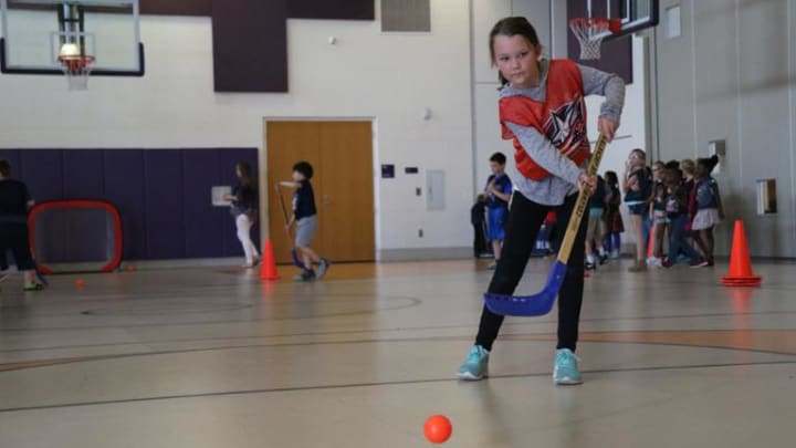 Photo of young girl shooting a ball with a hockey stick at a Hockey To Go clinic.