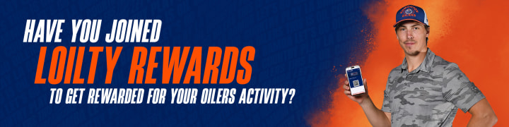 A promotional banner for "Loilty Rewards" features a blue and orange gradient background, matching the Edmonton Oilers’ team colors. On the left, large white and orange text asks, "Have you joined Loilty Rewards to get rewarded for your Oilers activity?" On the right, Ryan Nugent-Hopkins with a friendly expression wears a blue and orange Oilers cap and a gray camouflage shirt while holding up a smartphone that displays the Loilty Rewards app. The overall design is vibrant and energetic, encouraging fan participation.
