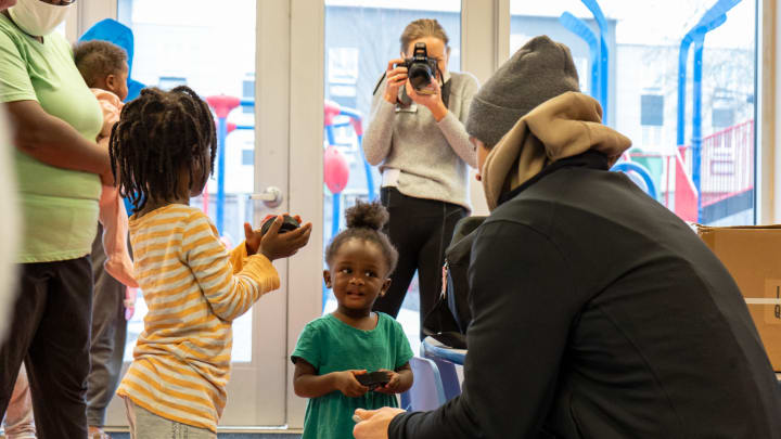 Photo of Blue Jackets player, Sean Kuraly, interacting with two young children at the Van Buren Center Family Shelter.
