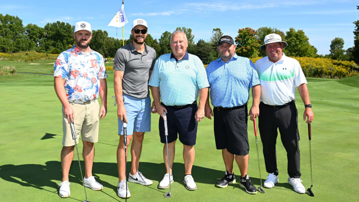 Photo of Blue Jackets player, Sean Kuraly, posing for a photo with a group of men on the golf course.