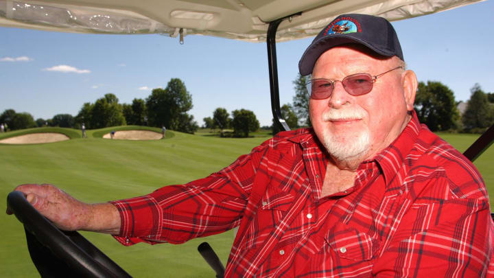 Photo of Team Founder, John H. McConnell, driving a golf cart on the golf course.