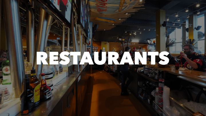 Photo of fans sitting at the bar of Bert's Bar at the Canadian Tire Centre with the word "Restaurants" in white letters.