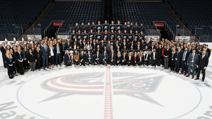 Group photo of Blue Jackets team and front office staff on the ice at Nationwide Arena.