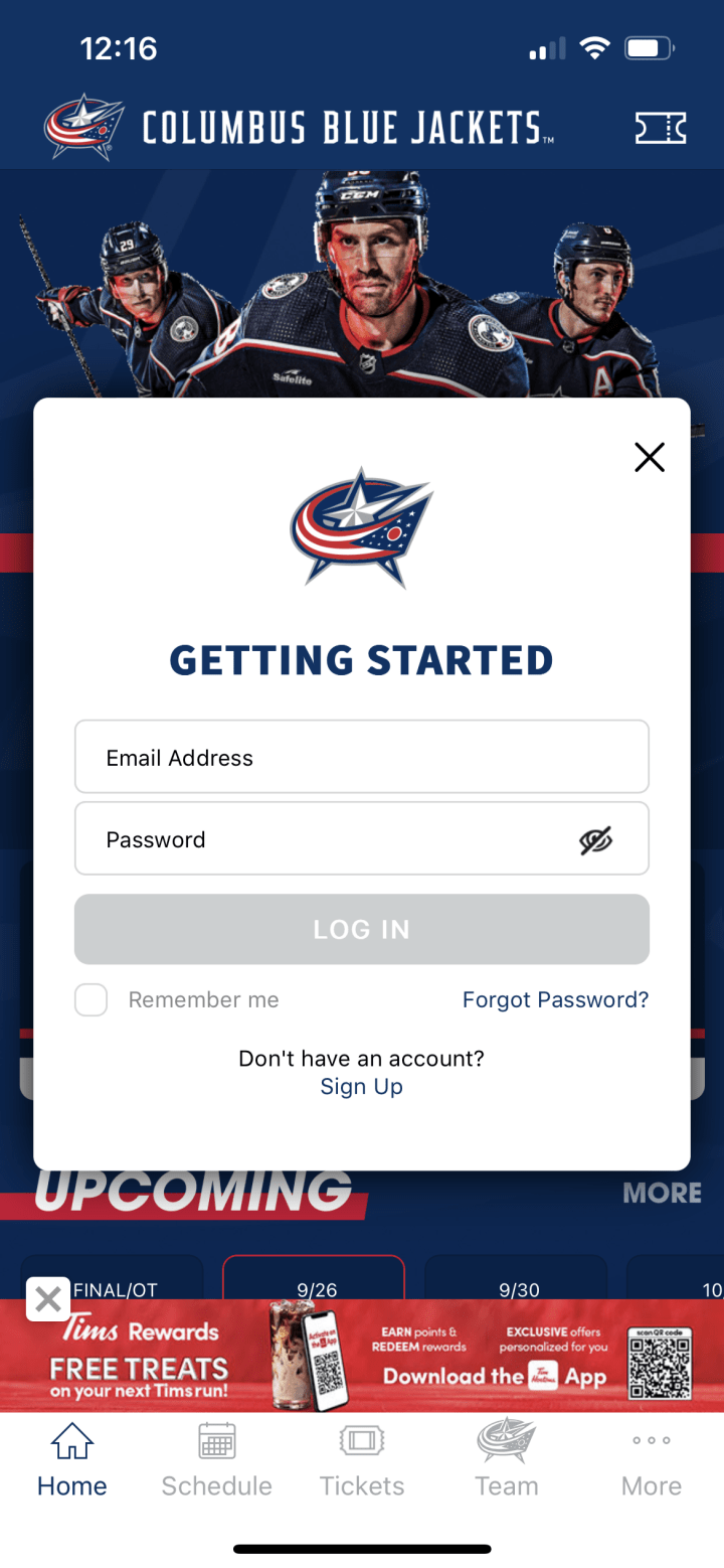 Screenshot of Blue Jackets App confirm profile screen. White overlay with blue text at the top reading Getting Started. Boxes below allow users to enter email address and password. Greyed out button reading Login is below the form fields. Checkbox below reads Remember me. Small blue text below reads Forgot Password? Small black text below reads Don't have an account? and Sign up.