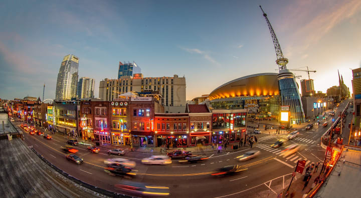 Fisheye lens, long-exposure photo overlooking Broadway to the southeast during the sunset. Bridgestone Arena is prominently poised on the right side of the image, ready for game day.